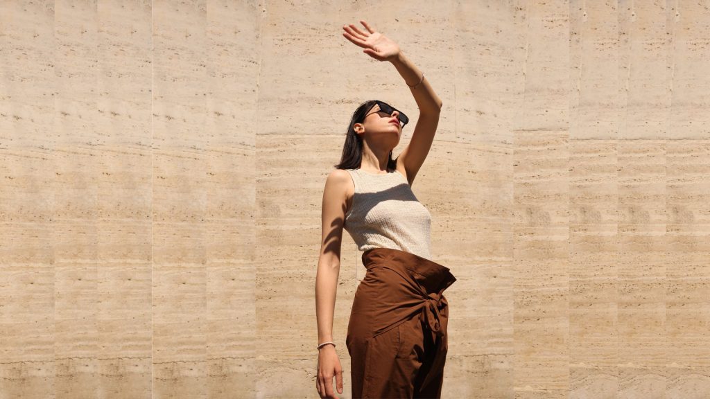 donna con occhiali da sole e una mano davanti al viso per proteggersi dal sole